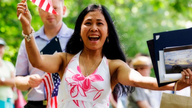 Woman holding flag at a naturalization ceremony.