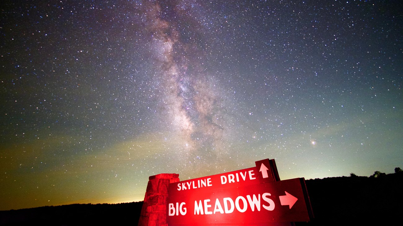 The Milky Way Galaxy cuts across the night sky above the Skyline Drive, Big Meadows sign.