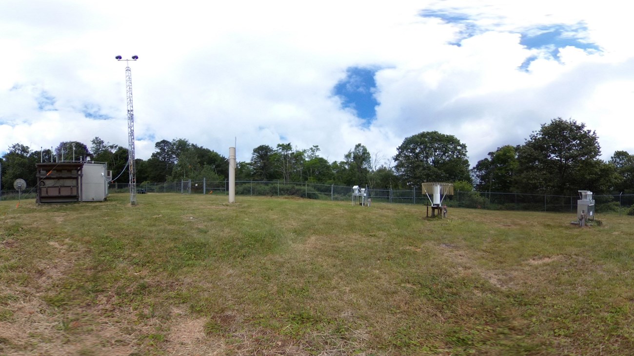 The air quality station consists of numerous measuring devices behind a fenced area.