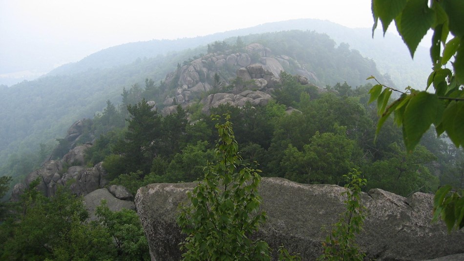 A misty scene of a mountain with large boulders.
