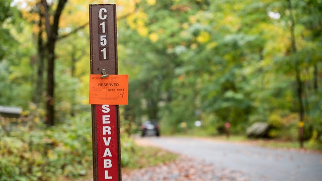 A red reservable site post with a site reserved notice clipped to the top. 