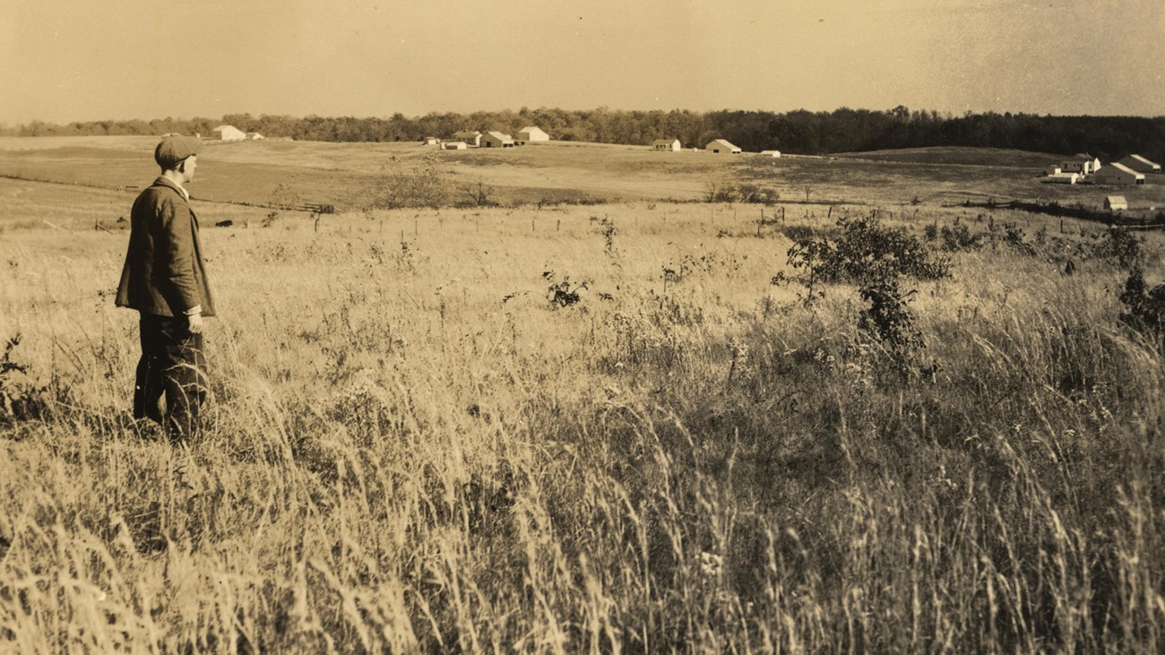 A historical image of a man looking across a field. 