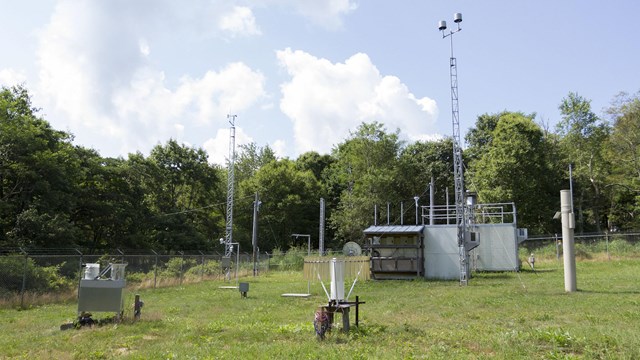 An air quality monitoring station, outdoors, with many scientific instruments scattered about.