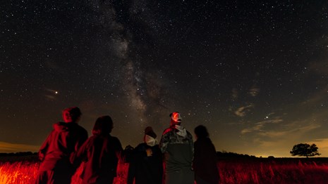 A nighttime photo of a small group of people gazing at a starry night sky.  