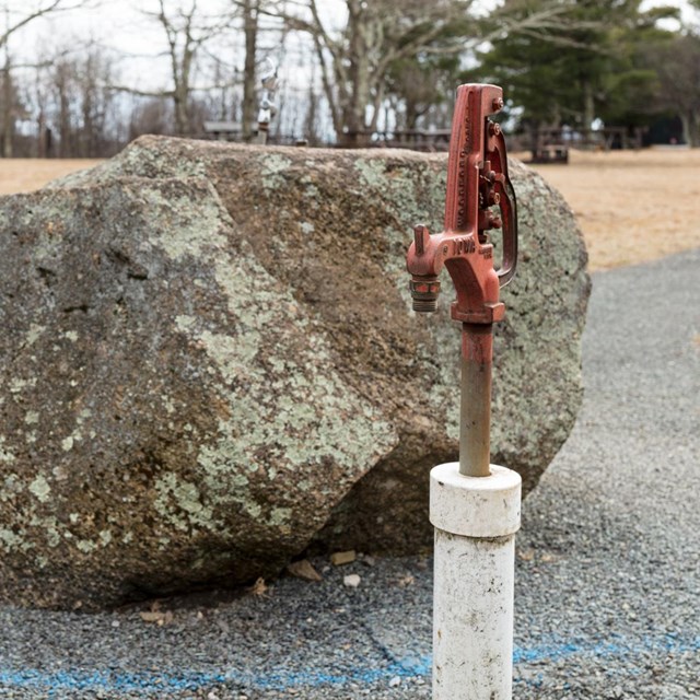 A close up of a water spigot in the middle of a developed campground.