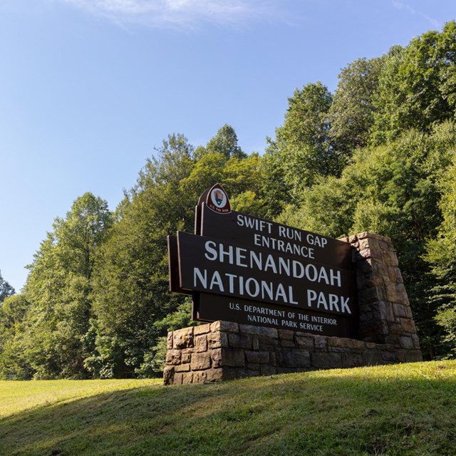 Shenandoah entrance sign on rock frame; blue skies above