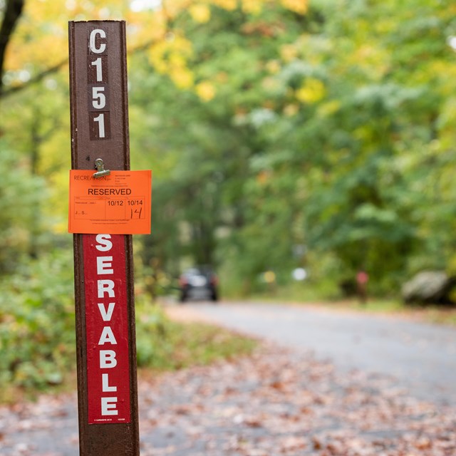 A red reservable site post with a site reserved notice clipped to the top. 