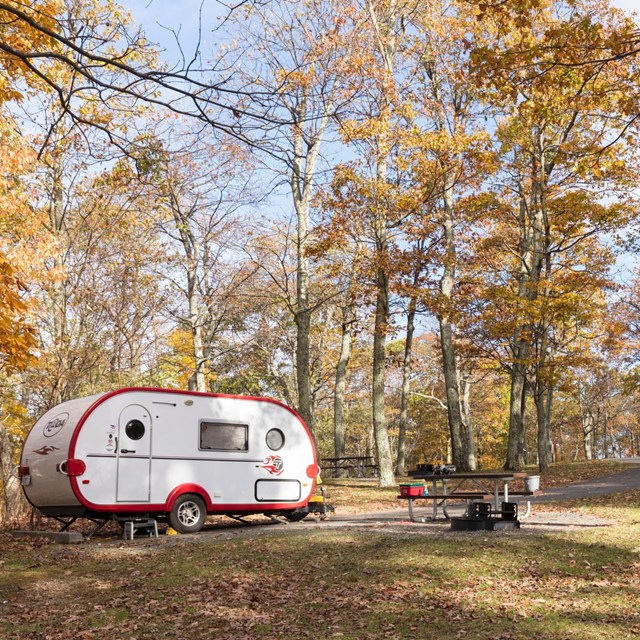A retro, white camper is set up at a campground.