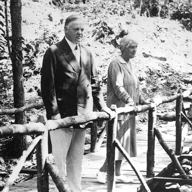 A historic photo of Mr. and Mrs. President Hoover on a bridge in the woods.