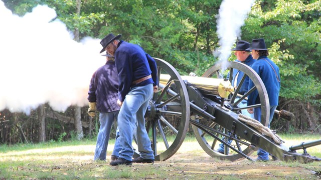 Living historians fire a cannon. 