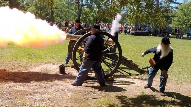 Living historians in Union uniforms fire a bronze cannon. 