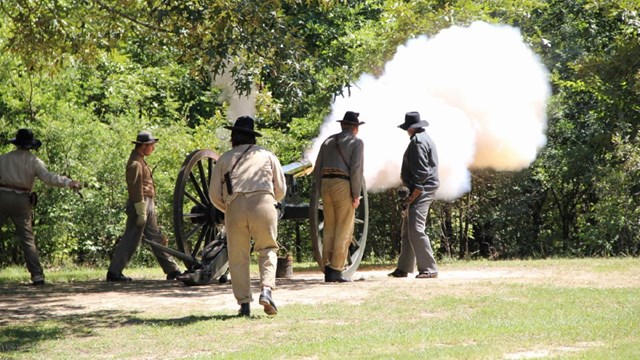 Flame bursts from the muzzle of a brass cannon. 
