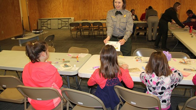 A female ranger helps three children