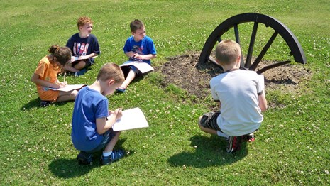 Photo of children working on activity books. Below the photo  "Become a Corinth Junior Ranger"