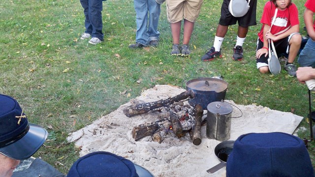 Image of food cooking on a campfire with the text "Places to Eat"