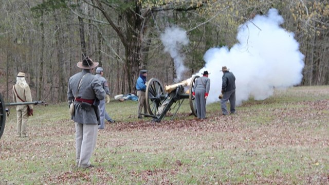 White smoke belches from a bronze gun. 