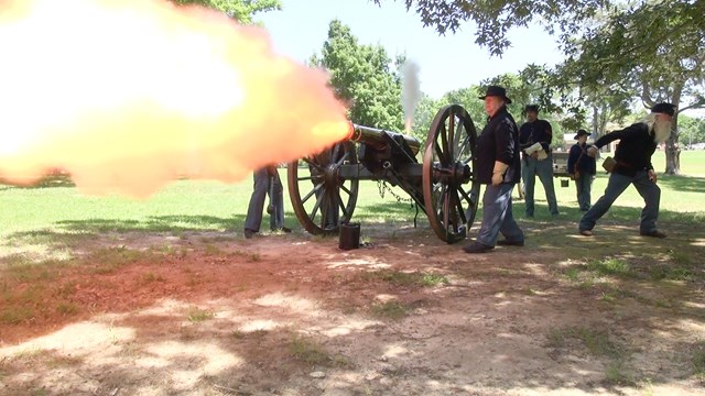 Living historians fire a cannon.