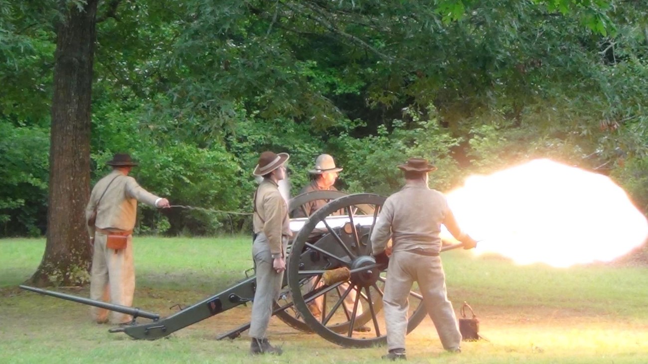 White smoke belches from a bronze gun. 