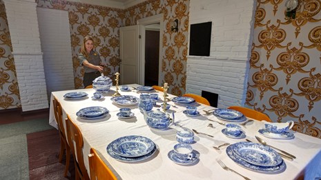 Park Ranger stands by the dining room table of the Russian Bishop's House.