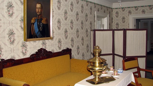 Table with samovar and tea cups with a portrait of the czar in the background