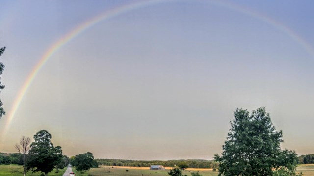 Photo or rainbow over highway with Port Oneida farm in background