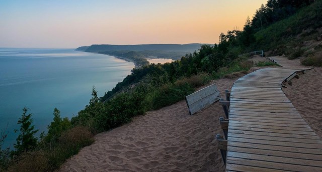 A wooden boardwalk on a high bluff with a view of a large lake beyond.