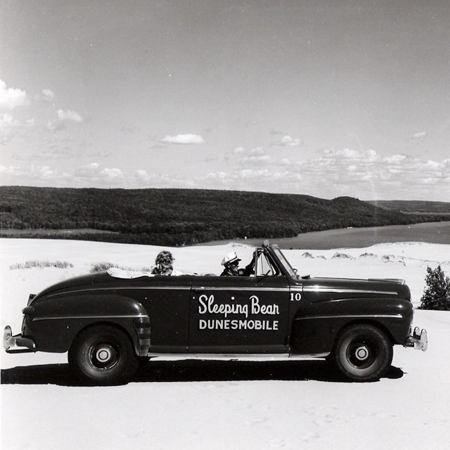 Black 1940s convertible with fat tires on the dune