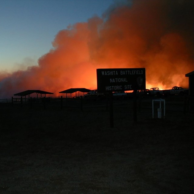 Billows of smoke glow from a prairie fire burning in the evening at Washita Battlefield