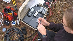Overhead view of an acoustic technician preparing microphone equipment for placement in the field