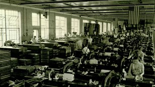 A black and white photo of rows of women working at machines. 