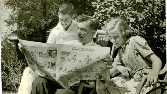 A parent with two kids reading the paper
