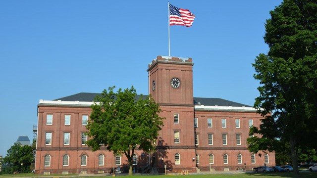 Brick building that serves as the museum. American flag waves on the top of the clock tower.