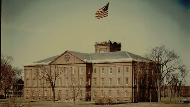 The Main Arsenal building from the rear with the flag at full staff blowing in the wind. 