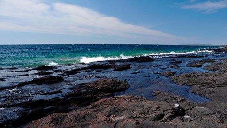 Waves crash on a bedrock shelf along the shore of Lake Superior.