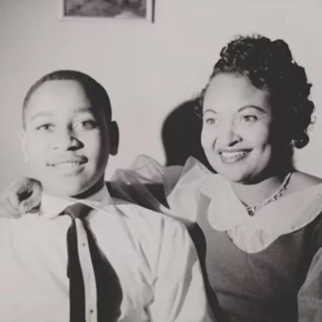 A black and white photo of Emmett Till and Mamie Till-Mobley dressed up and smiling.
