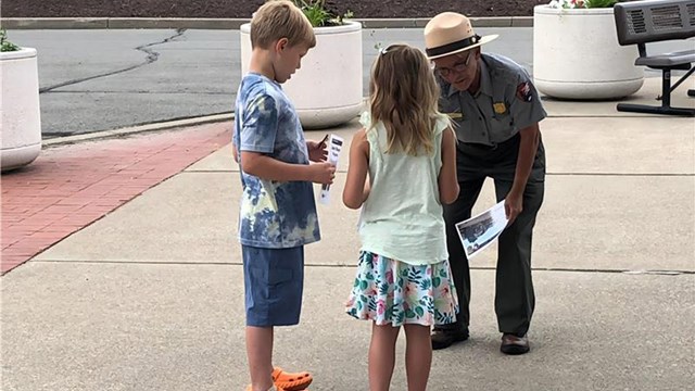 A Ranger helps two children with their Junior Ranger activities 