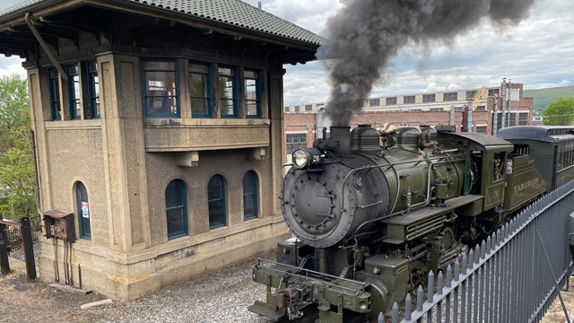 Photo of Locomotive with Smoke and Steam passing a Signal Tower