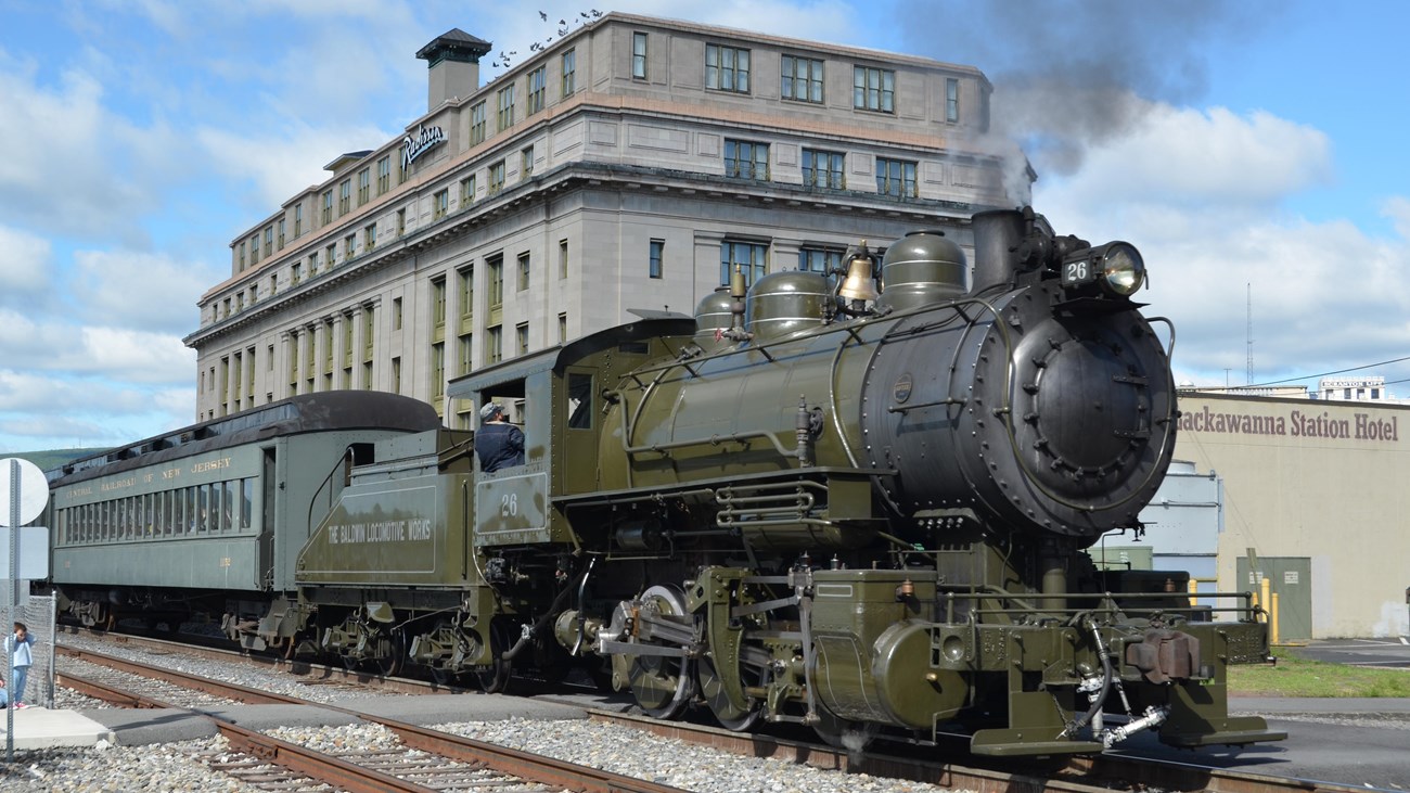 Steam engine traveling toward camera past Lackawanna Station Hotel