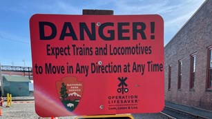 A post with two signs. Top sign is red and reads "danger" bottom sign is yellow and is warning