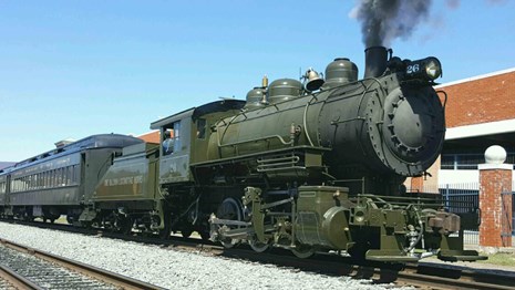 Small steam locomotive in green paint, while lettering