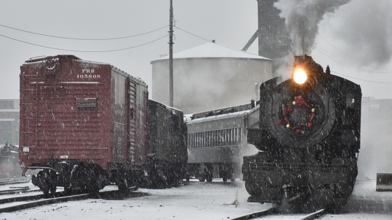 Steam engine traveling toward camera on a snowy day