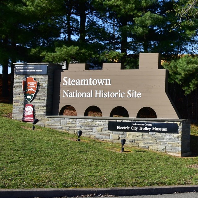 train shaped steamtown nhs entrance sign on left, flowers on right