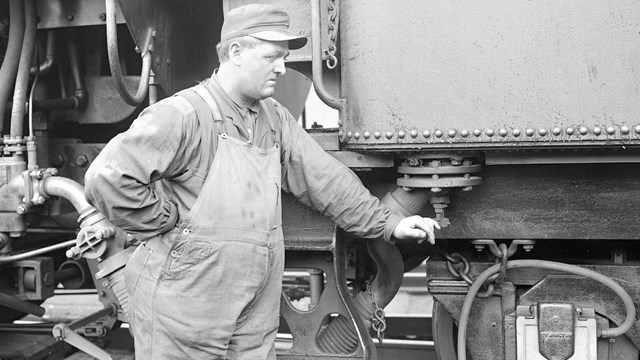 Railyard engineer next to locomotive