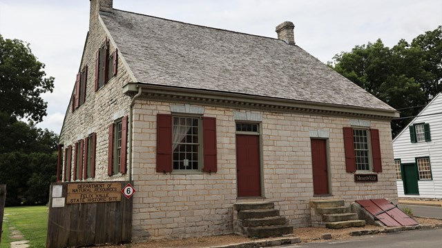 A small stone house with two red front doors. 