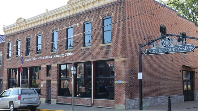 A brick building with two large windows on the first floor. 