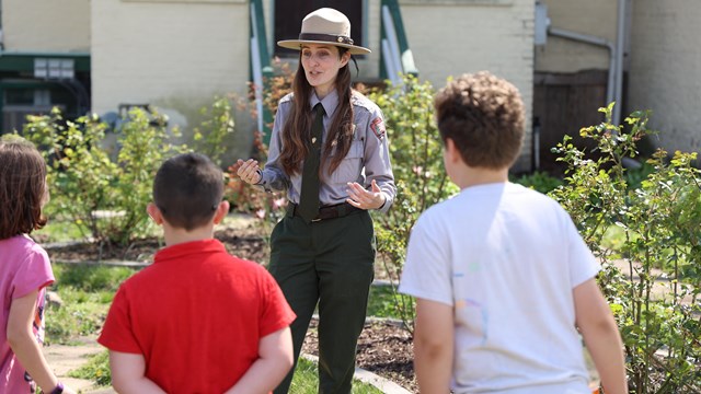 Ranger in front of a group kids in a garden.