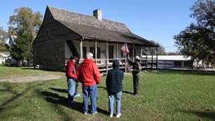 Park Ranger standing in front of historic home with a group of four talking to the group.