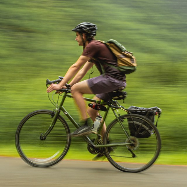 a man wearing a helmet bicycles on a path