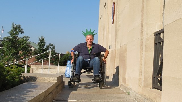 A visitor in a wheelchair is moving down a ramp towards the image.