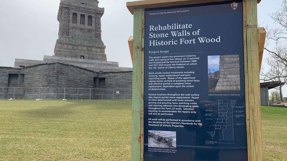 A sign on the side of Liberty island explains the work happening on Fort Wood in the background